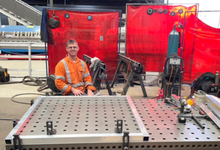 Man in highly visual clothing sitting at his workstation in the boilermaker's shop